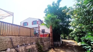 A house with a stone wall, a metal fence, and a palm tree. - Country House 'Cucazorra' with Mountain View, Wi-Fi and Air Conditioning (Málaga)