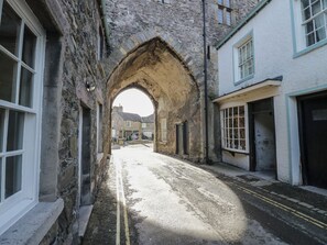A narrow street with stone buildings, an archway, and a double yellow line road. - Flat 4 Tower House (Grange-over-Sands)