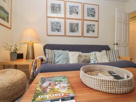 A neatly arranged bedroom with a bed, bedside table, lamp, and a magazine on the table.
