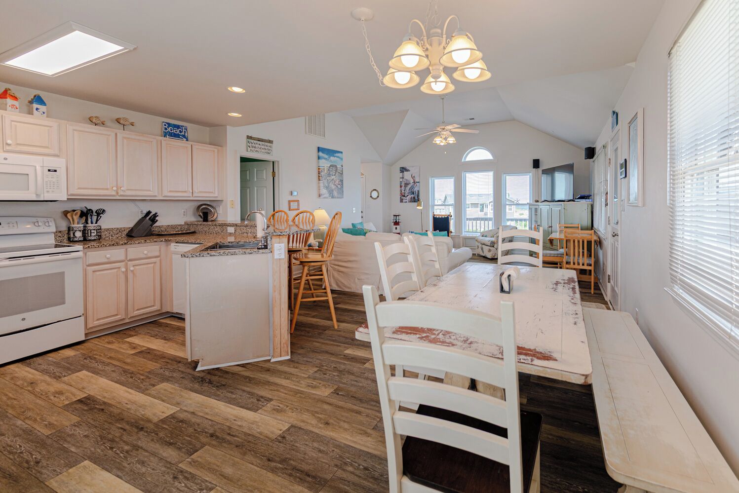 A kitchen with white cabinets, a dining area with wooden chairs, and a large island.