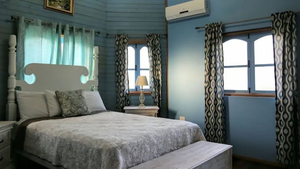 Un dormitorio con cama, mesita de noche, lámpara y ventana con cortinas estampadas.