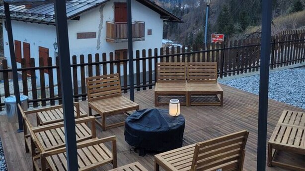 En træterrasse med udendørs møbler og et bjerg i baggrunden.