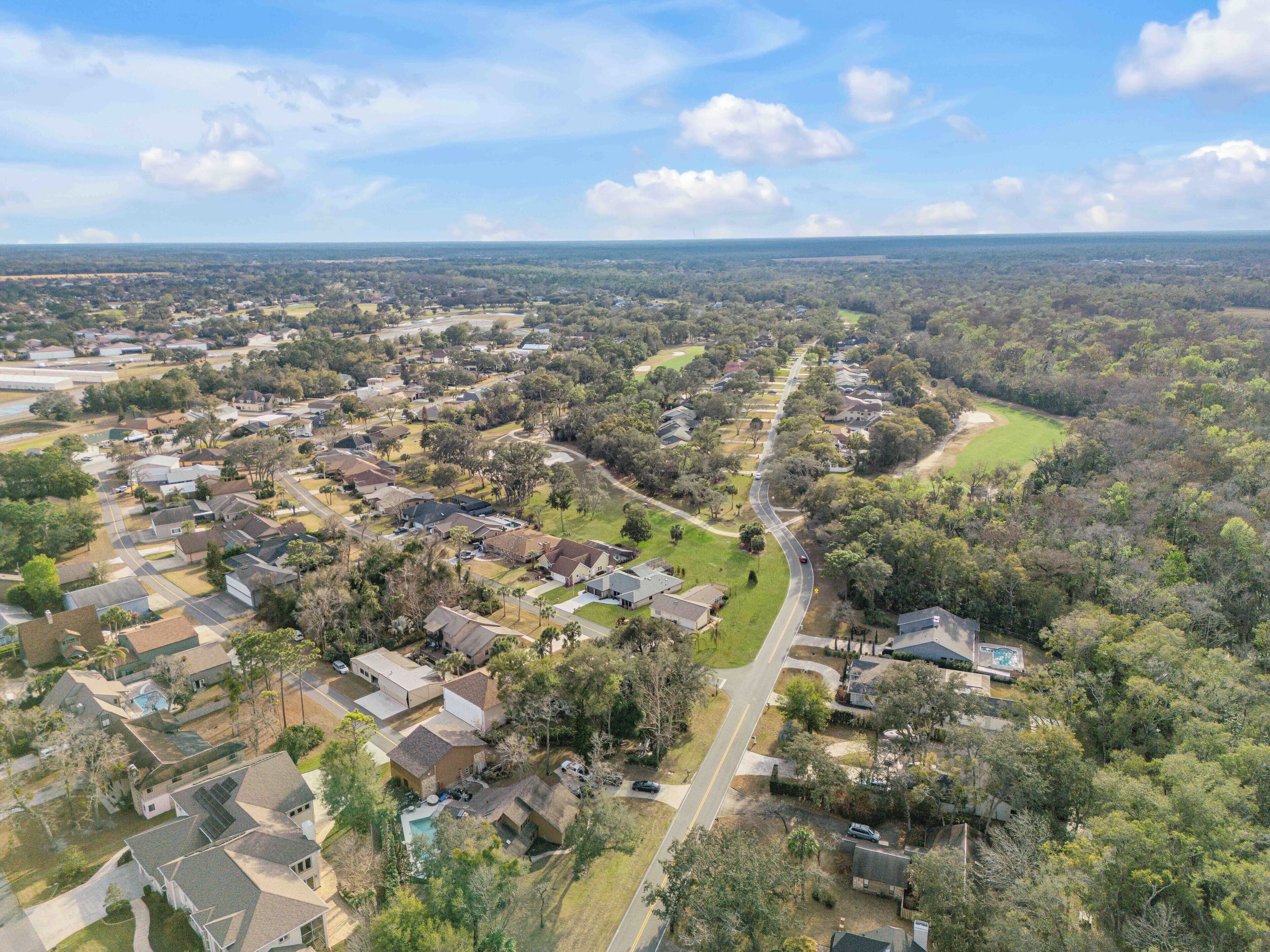 An aerial view of a residential area with houses, roads, and green spaces.