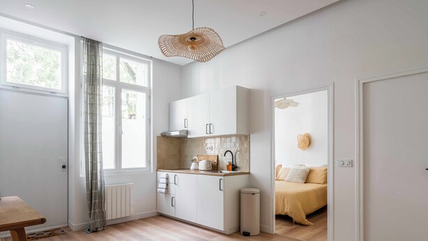 Una cocina moderna con armarios blancos, encimera de madera y una lámpara colgante.