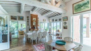Un comedor amplio con una mesa grande y sillas, techo de madera y vistas al exterior a través de ventanas amplias.