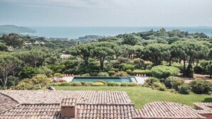 Vista de una propiedad con piscina rodeada de exuberante vegetación y una lejana vista al mar.