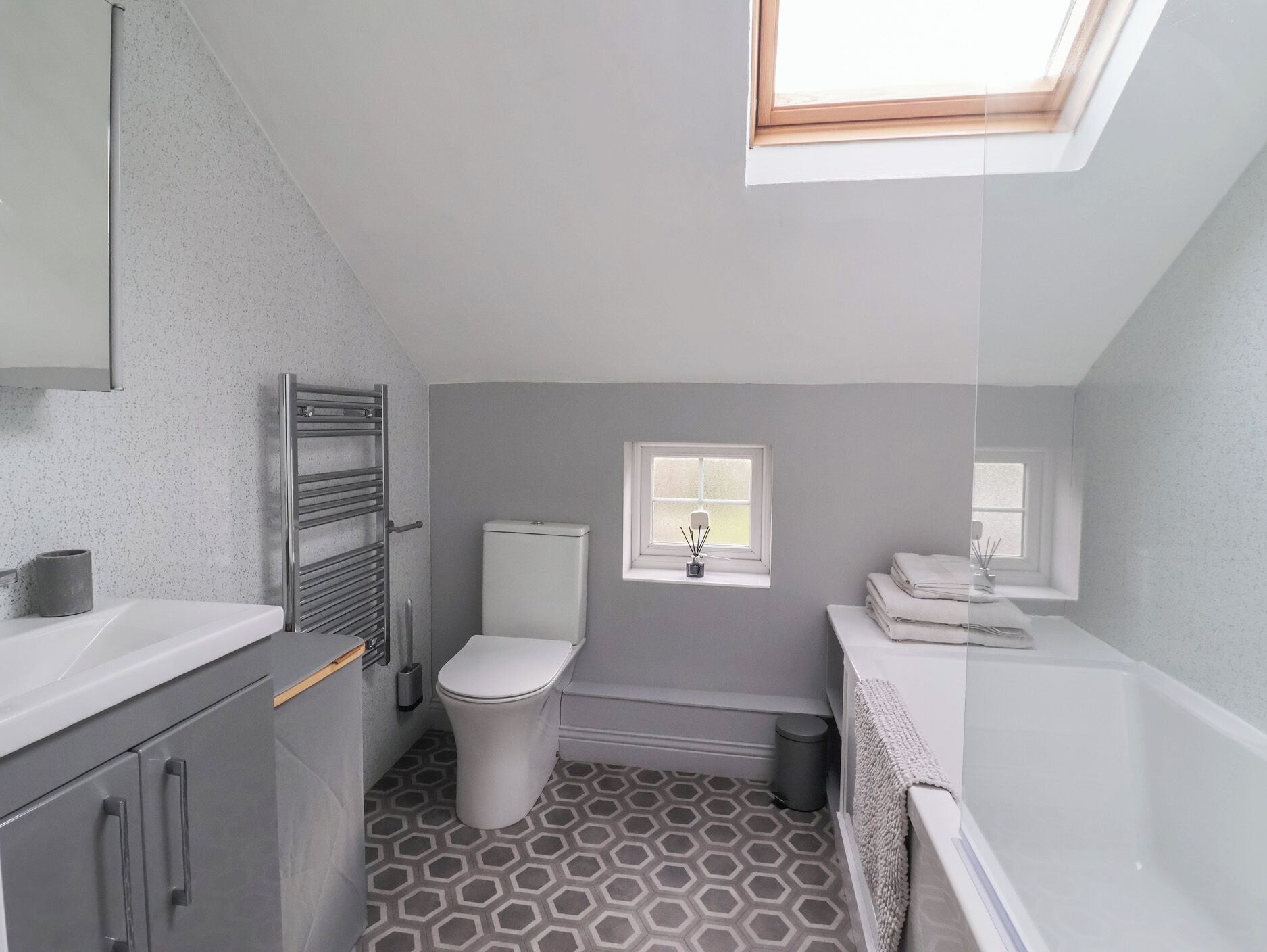 Une petite salle de bain avec un puits de lumière, des toilettes, un lavabo et une petite fenêtre.