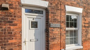 Een witte deur met het nummer 4, een raam met zonwering, en een bordje met de tekst 'Grange Cottage 4 Main Street Grange Farm Properties Ltd'.