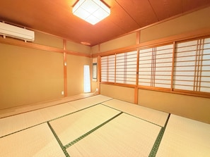 Una habitación japonesa tradicional con suelo de tatami, puertas correderas shoji y un ventilador de techo.