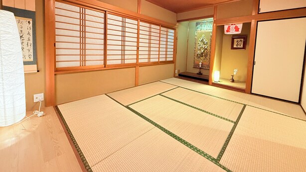 Ett traditionellt japanskt rum med tatamimattor på golvet, skjutdörrar och en shoji-skärm.