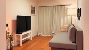 Ett modernt vardagsrum med en grå soffa, ett vitt TV-bord och ett trägolv.