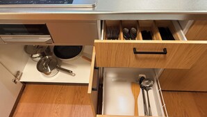 Ett kök med en inbyggd spis, en låda med köksredskap och en kastrull på bänkskivan.