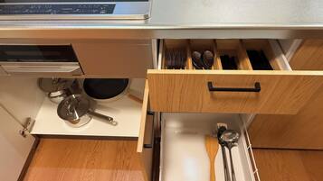 A kitchen with a built-in stove, a drawer with utensils, and a pot on the countertop.