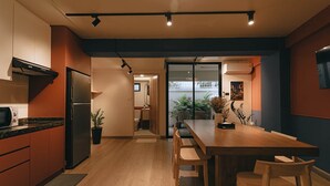 Een moderne keuken met een ingebouwde koelkast, houten keukenkastjes en een eethoek met een houten tafel en stoelen.