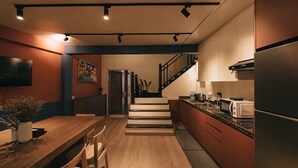 Een moderne keuken met een houten eettafel, inbouwapparatuur en een trap naar een hoger niveau.