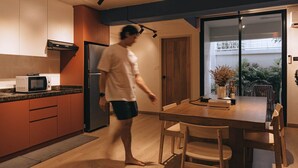 Een moderne keuken met een magnetron, koelkast en een houten eettafel met stoelen.
