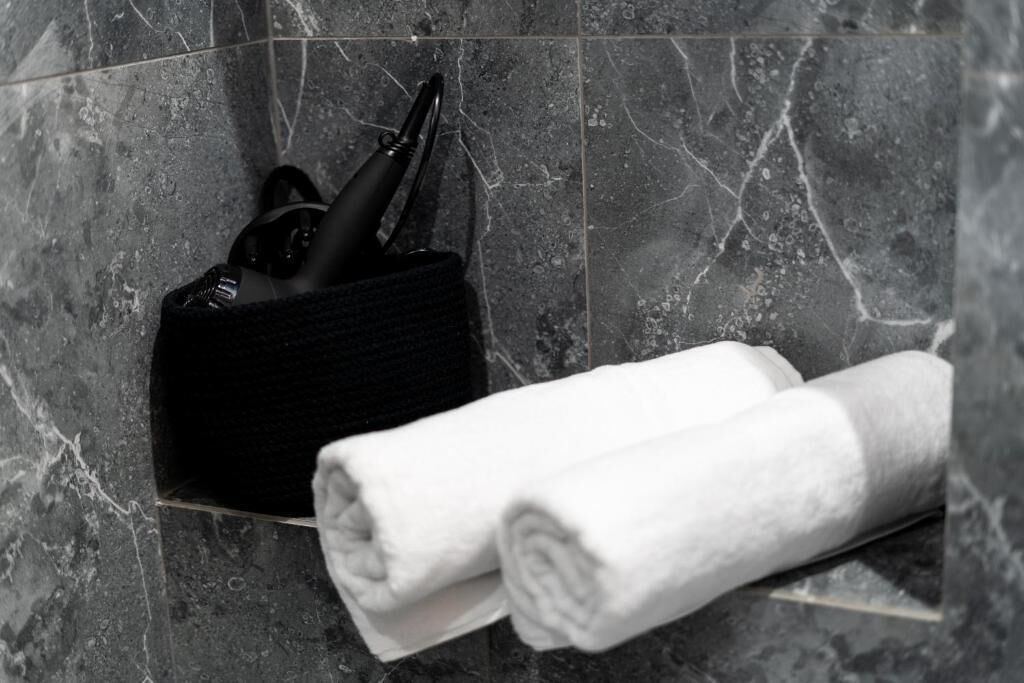 A bathroom with a marble floor, a black towel holder with a towel, and a black bag.