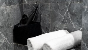 A bathroom with a marble floor, a black towel holder with a towel, and a black bag. - Malila Apartments Cracow Grzegórzecka 15 (Kraków)