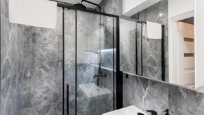 A modern bathroom with a glass-enclosed shower, a white sink, and a large mirror. - Malila Apartments Cracow Grzegórzecka 15 (Kraków)
