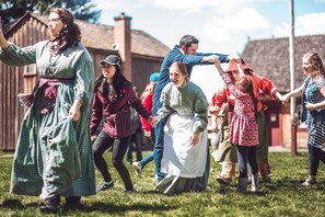 Un grupo de personas con vestimenta histórica en un campo cubierto de césped.