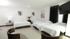 A hotel room with three single beds, a flat-screen TV, a small table with a lamp, and artwork on the walls. - Hotel La Sultana  (Tumaco)
