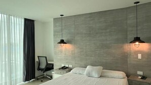 A modern bedroom with a large bed, two bedside tables, a desk, and a chair. - Hotel La Sultana  (Tumaco)