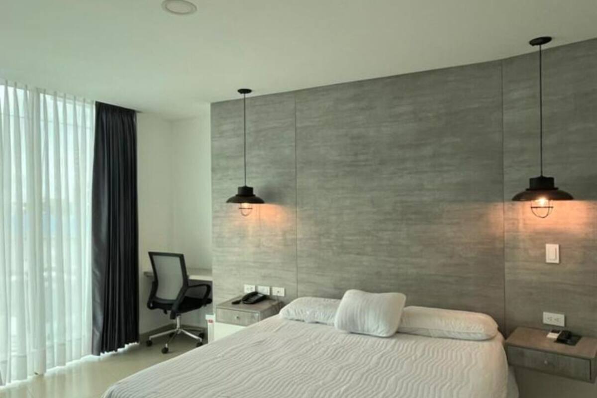 Une chambre à coucher moderne avec un grand lit, deux tables de chevet, un bureau et une chaise.
