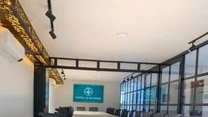 A conference room with a long table, black chairs, and a large window. - Hotel La Sultana  (Tumaco)