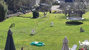 A grassy backyard with a trampoline, a picnic table, and a covered seating area. - Large family home in the heart of Redon near the train station (Redon)