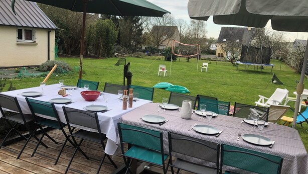 An outdoor dining area with tables set for four, green chairs, and large umbrellas providing shade. - Large family home in the heart of Redon near the train station (Redon)