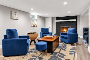 A modern living room with blue sofas, a coffee table, and a fireplace. - Evergreen Acres • Woodland Preserve • Private Pool (South Haven)