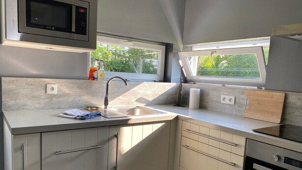 A compact kitchen with a microwave, sink, and oven. - Holiday Home "In the Heart of Nature" with Private Terrace, Shared Garden & Wi-Fi (Ambleteuse)