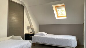 A small, single-room apartment with two beds, a skylight, and a door. - Holiday Home "In the Heart of Nature" with Private Terrace, Shared Garden & Wi-Fi (Ambleteuse)