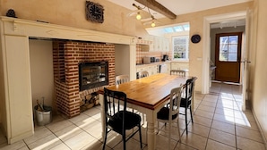 A kitchen with a brick fireplace, wooden table, and chairs, with a view to the outside. - Charming renovated farmhouse - sleeps 6 (Boismont)