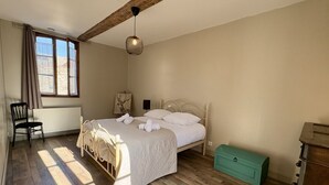 A bedroom with a bed, a chair, a dresser, and a window with curtains. - Charming renovated farmhouse - sleeps 6 (Boismont)