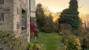 Un bâtiment en pierre avec un sentier de jardin menant à une pelouse.