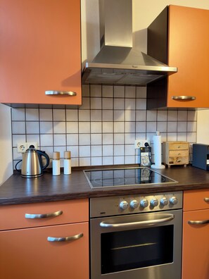 Una cucina con fornelli, forno e cappa aspirante.