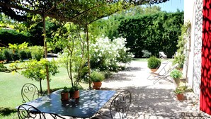 A patio with a table and chairs, surrounded by potted plants and a garden. - Holiday Home 'Chez Maté et Francis' with Private Terrace, Garden & Wi-Fi (Saint-Rémy-de-Provence)