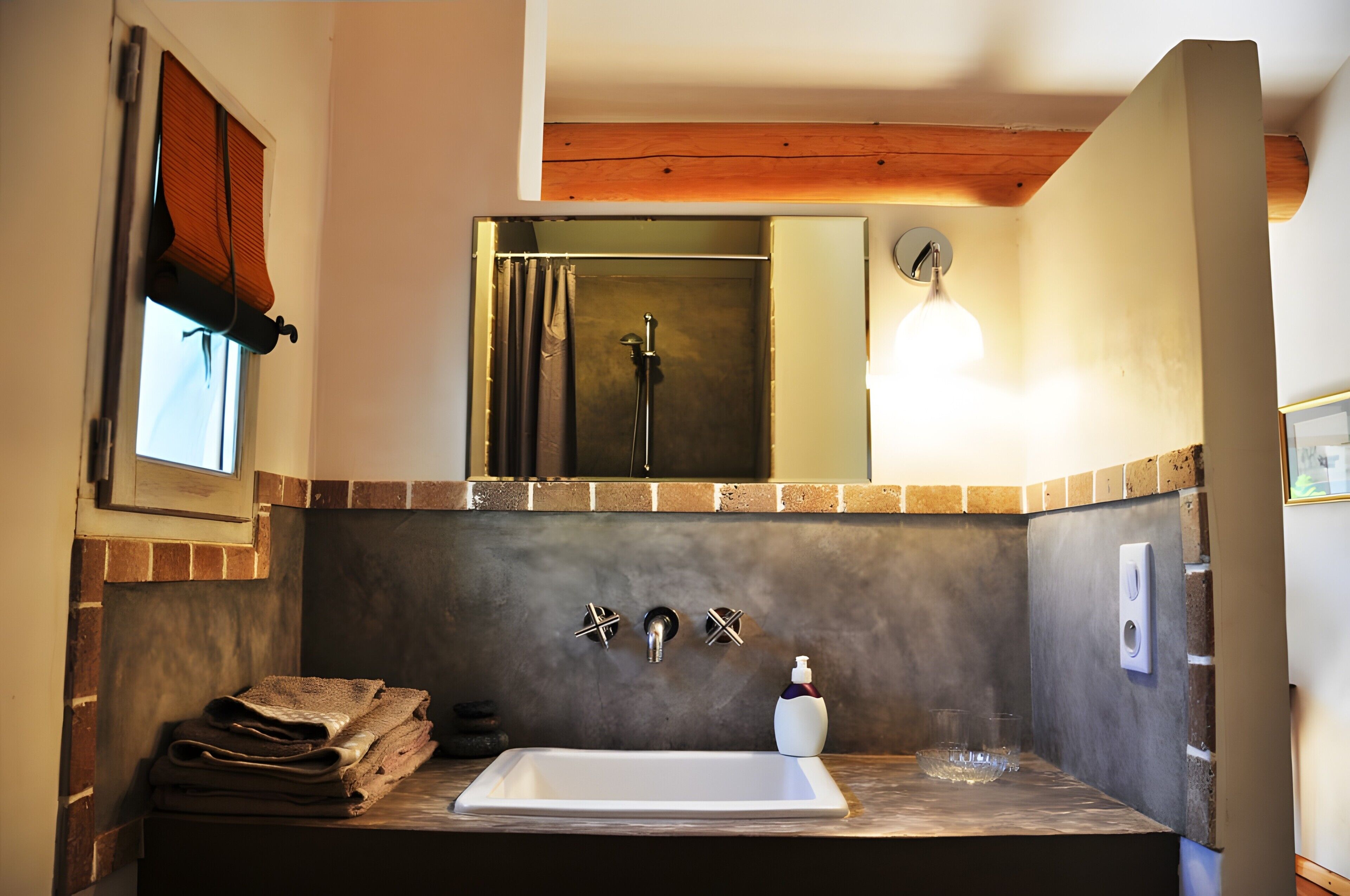 Une salle de bain équipée d’un lavabo, d’un miroir, d’une pile de serviettes et d’une douche.