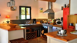A compact kitchen with a wooden countertop, a sink, a stove, a microwave, and a red cabinet. - Holiday Home 'Chez Maté et Francis' with Private Terrace, Garden & Wi-Fi (Saint-Rémy-de-Provence)
