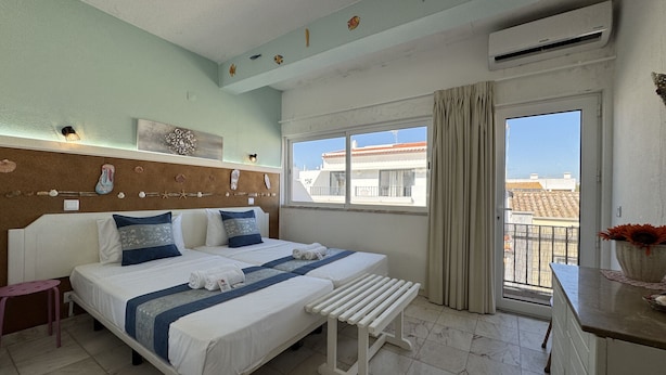 Ein Hotelzimmer mit Bett, einer Sitzbank, einem Fenster mit Blick und einer Wand, die mit Muscheln und Fischen dekoriert ist.