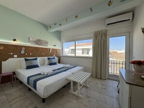 Een hotelkamer met een bed, een bankje, een raam met uitzicht en een muur versierd met schelpen en vissen.