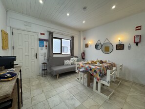 A dining area with a table set for breakfast, a sofa, and a window with curtains.