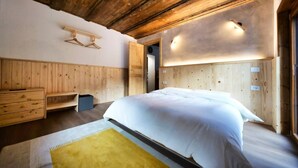 A bedroom with a wooden headboard, a bed with white bedding, a bench, and a small table. - Apt.Cristallo - `La Baita Civetta 1955` (Le Grazie)