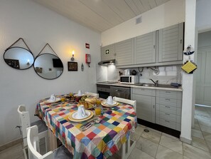 Un coin repas avec une table mise pour le petit-déjeuner, un four à micro-ondes et un évier dans la cuisine adjacente.