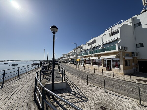 Une promenade en bord de mer avec une allée en bois, un lampadaire et des bâtiments abritant des boutiques.