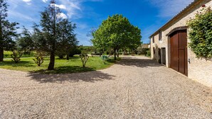 A gravel driveway leading to a building with a stone facade and a wooden door.