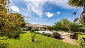 A house with a paved patio, a lawn, and a clear sky.