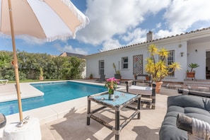 A poolside area with a table, chairs, and a sofa.