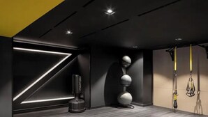 A modern gym with a minimalist design, featuring a pull-up bar, a stationary bike, and a wall-mounted exercise ball.